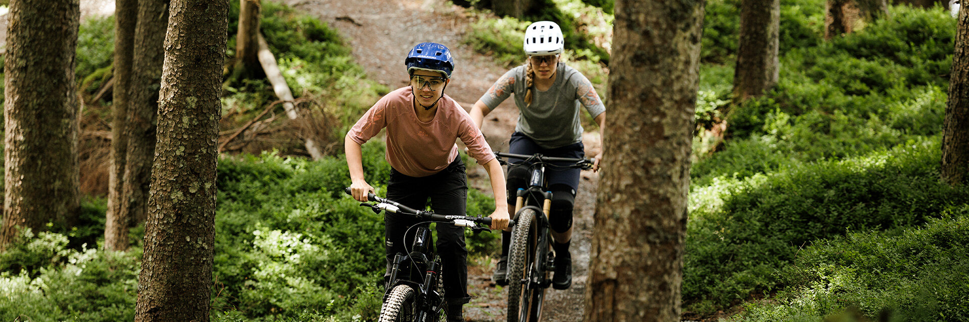 Deux utilisateur de VAE / cycliste / sportif à VAE roulent l’un derrière l’autre sur un sentier forestier.