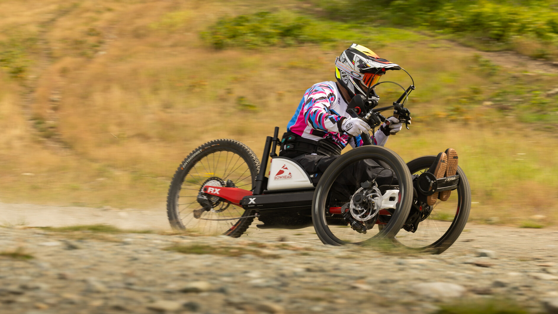 Tarek Rasouli fährt in seinem Handbike mit Helm und Schutzausrüstung eine steile und kurvige Abfahrt in einem Bikepark hinunter.