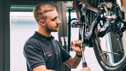 The bicycle mechanic uses tools to repair an eBike.