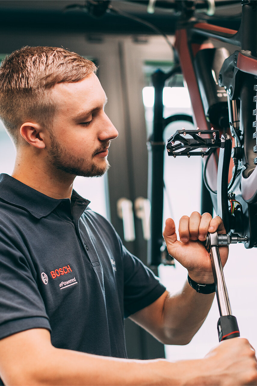 The bicycle mechanic uses tools to repair an eBike.