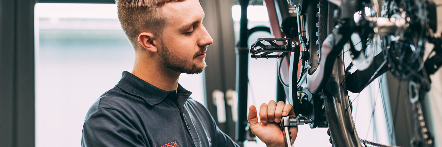 Fahrradmechaniker verwendet Werkzeug, um ein eBike zu reparieren.