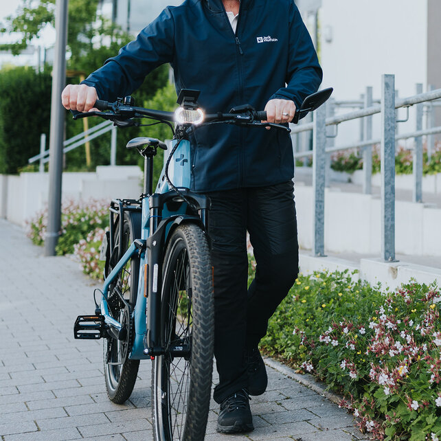 A man pushes his eBike on a sidewalk.