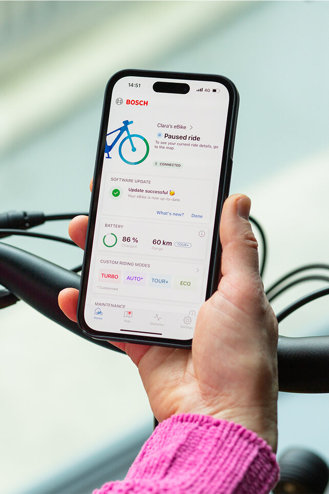 Vista sopra la spalla di una persona che tiene in mano uno smartphone con l'app eBike Flow aperta.