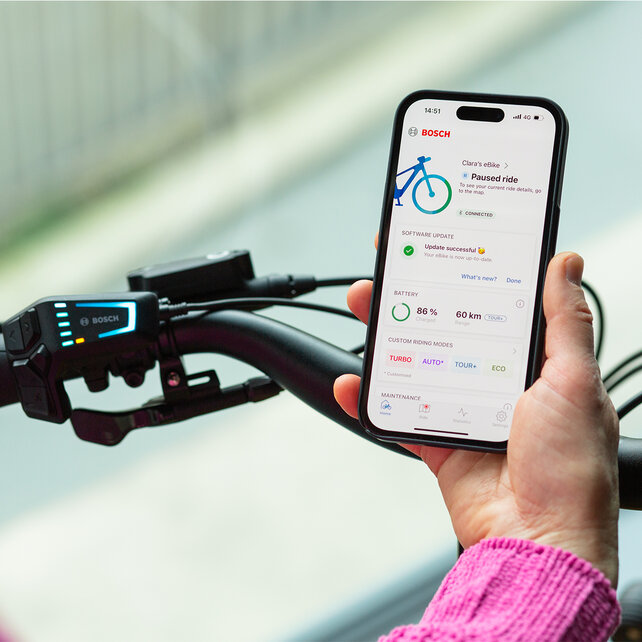 Vue par-dessus l’épaule d’une personne tenant un smartphone affichant l'application eBike Flow ouverte.