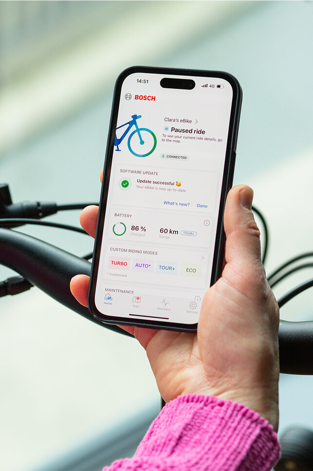 Over-the-shoulder view of a person holding a smartphone with the eBike Flow app open.