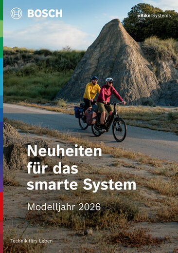 Cover einer Produktbroschüre mit dem Text "Neuheiten für das smarte System", darunter "Modelljahr 2025". Als Hintergrundbild sind zwei eBiker zu sehen.  Oben rechts steht "eBike Systems".