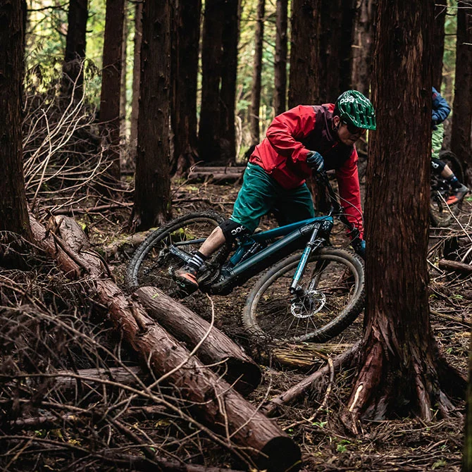eBike-Fahrer fährt abseits des Weges durch den Wald, umgeben von vielen Ästen, die auf dem Boden liegen.