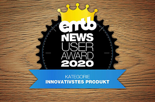 Icon with the text "emtb NEWS USER AWARD 2020": A golden crown above the text, surrounded by a black circle. At the bottom, it states "CATEGORY MOST INNOVATIVE PRODUCT". The background has a wooden texture.