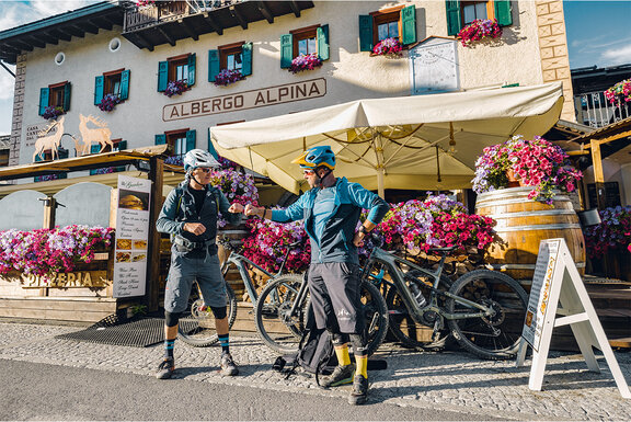 Dos ciclistas de eBike se encuentran frente a un restaurante y chocan sus puños.