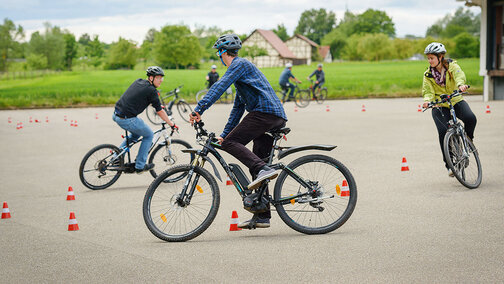 Utilisateur de [eBike] sur un terrain d'entraînement à la circulation équipé de cônes de signalisation.