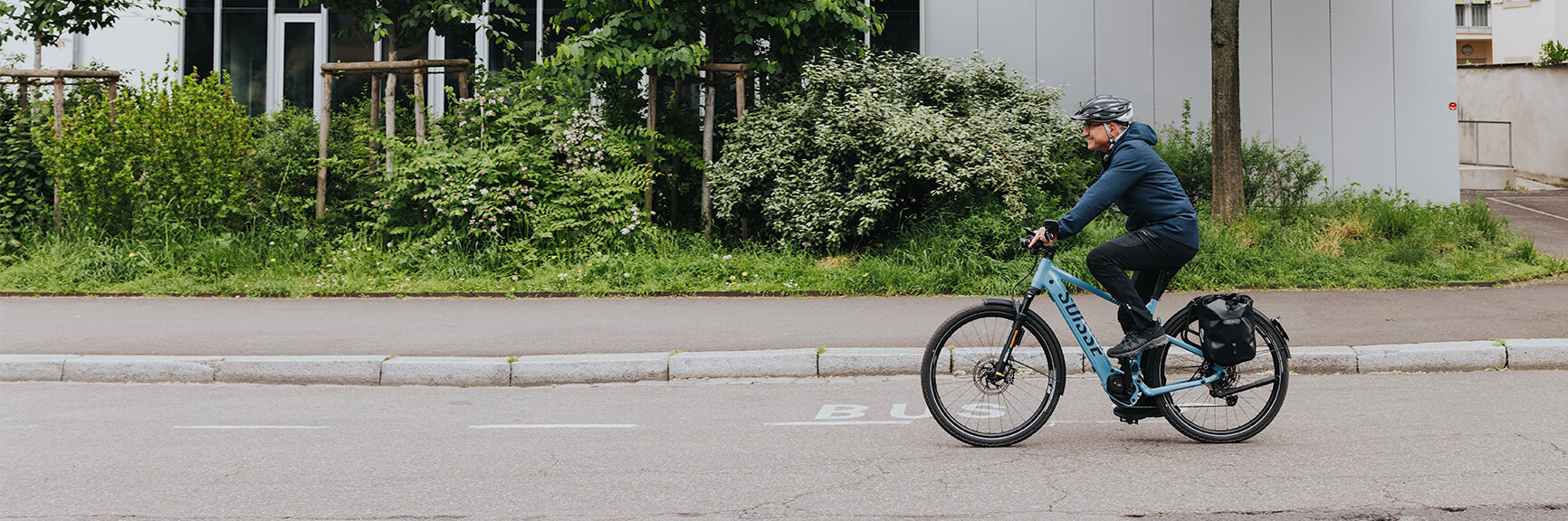 A man is riding his eBike quickly along a street in a residential area.