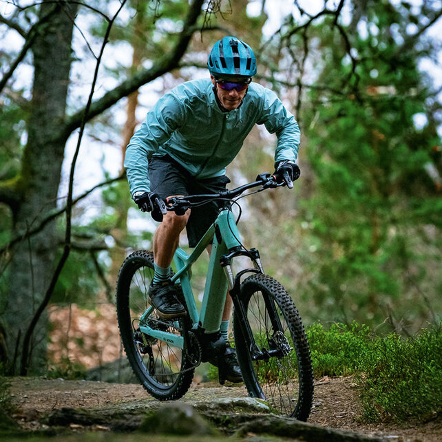 En e-mountainbike-rytter sykler langs en skogsvei.
