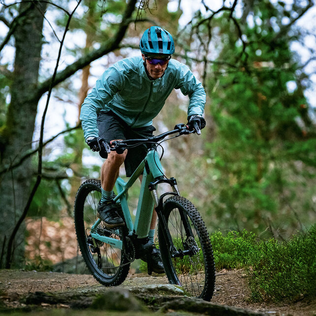 Un VTT à assistance électrique conduit le long d’un chemin forestier.