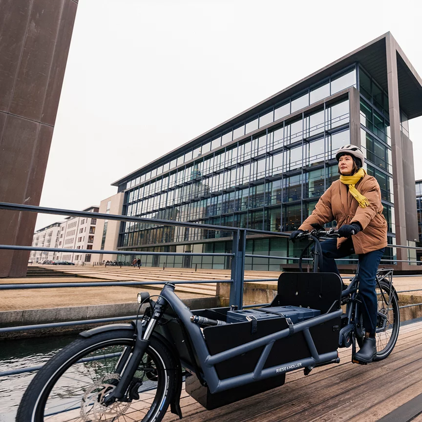 Sofie Birc is riding an eCargo bike across a wooden bridge.