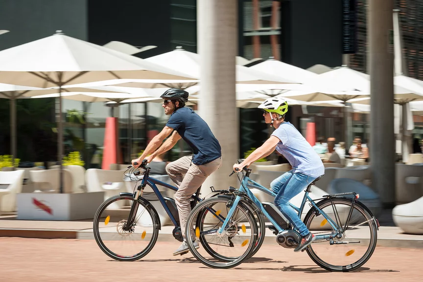 Ein Mann und eine Frau fahren auf ihren eBikes an einem Restaurant vorbei.