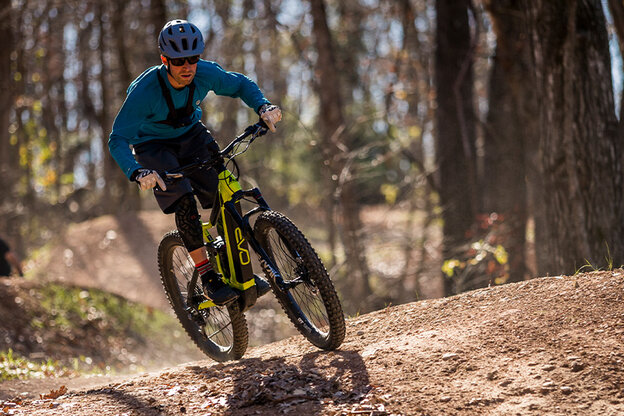 An eMountain bike rider climbs a hill in the forest.