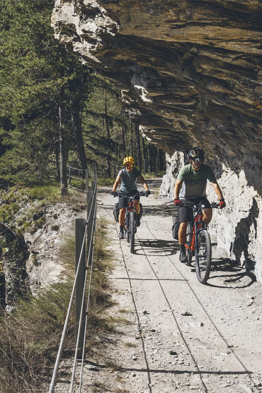 Deux VAE roulent sous un rebord rocheux.