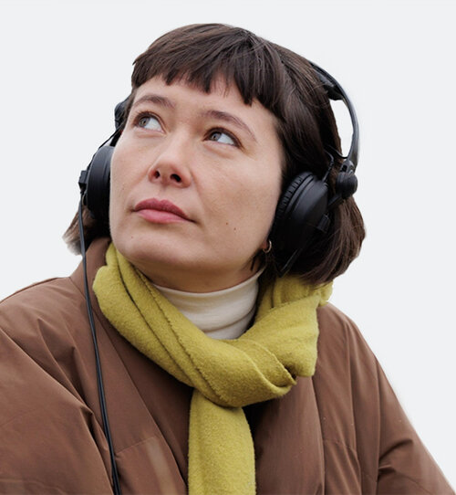 Portrétní fotografie Sofie Birc s sluchátky, která hledí do dálky.
