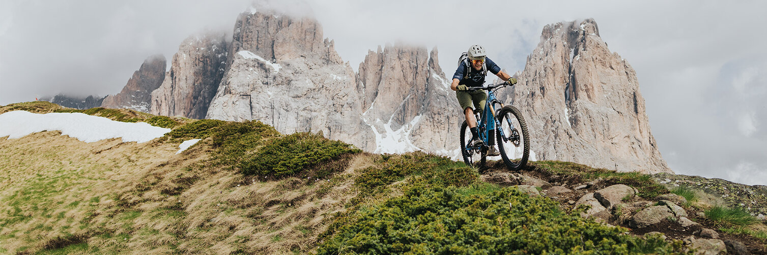 Uno scatto di un paesaggio montagnoso con un ciclista di eMountain su un sentiero.