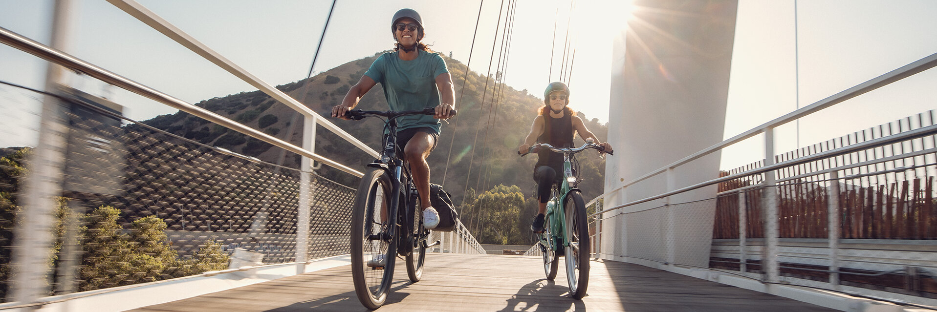 Zwei eBiker fahren über eine Brücke.