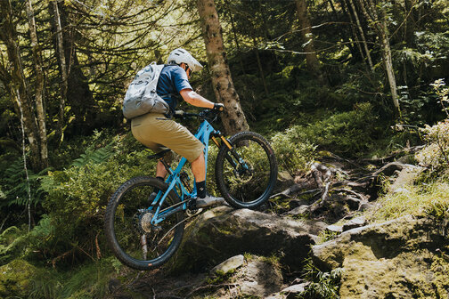 An eBiker rides over wood and stones on a forest trail in Sasbachwalden.