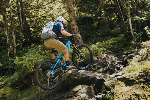 Ein eBiker fährt über Holz und Steine auf einem Waldweg in Sasbachwalden.