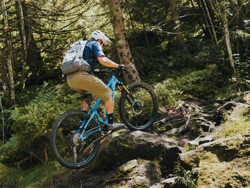 An eBiker rides over wood and stones on a forest trail in Sasbachwalden.