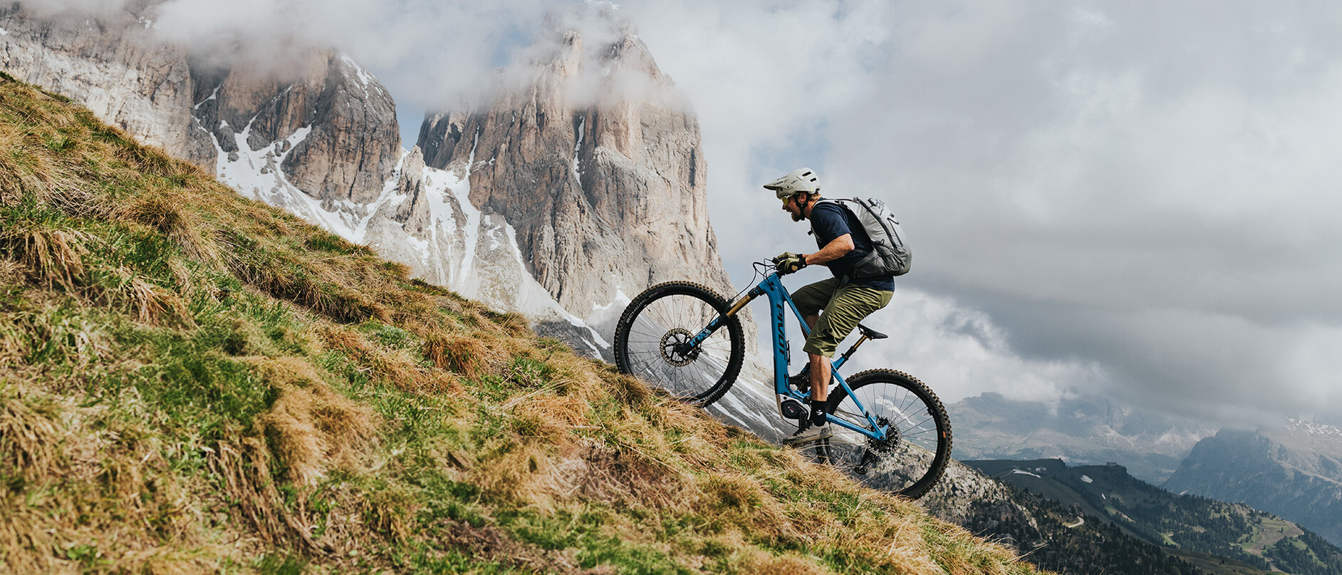 Mann fährt mit einem eMountainbike einen steilen Hang hinauf, umgeben von nebliger Landschaft.