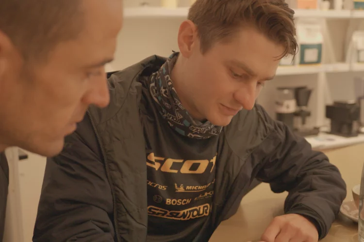 Deux hommes en gros plan, assis à une table et la regardant ensemble.