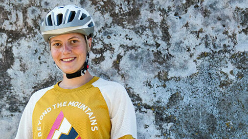 Greta Weithaler steht mit ihrem eMountainbike vor einer Felswand