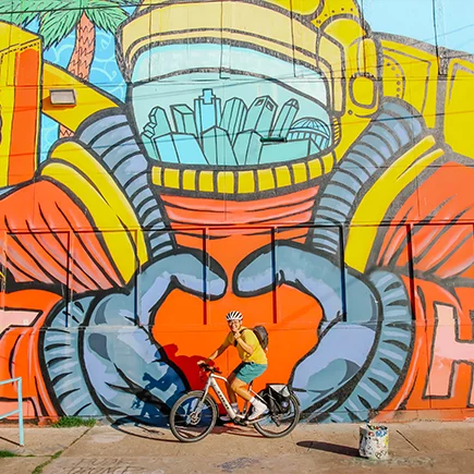 A man is seen riding an eBike with a Bosch drive unit in front of a mural in Houston, Texas.