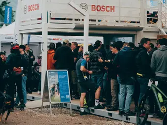 A group of people, some dressed in cycling gear, stands on a platform featuring the Bosch logo.