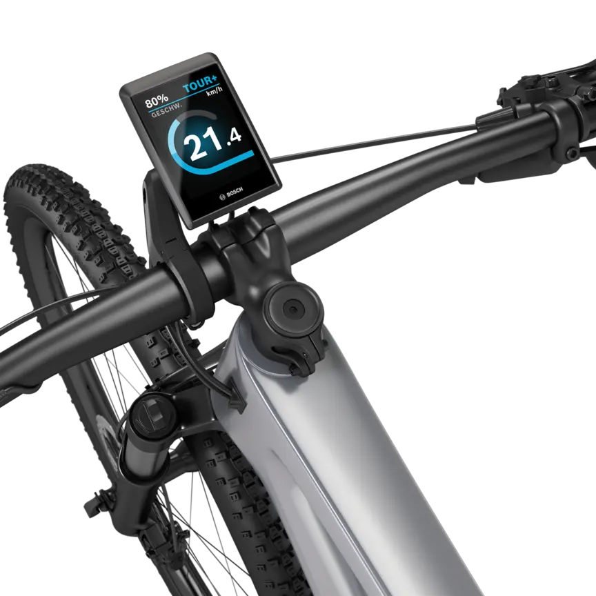 Ein silbernes eMountainbike mit schwarzem Lenker freigestellt vor weißem Hintergrund. Am Lenker ist ein Kiox 500 montiert. Das Display zeigt die Geschwindigkeit in km/h, den Akkustand und den Fahrmodus an.