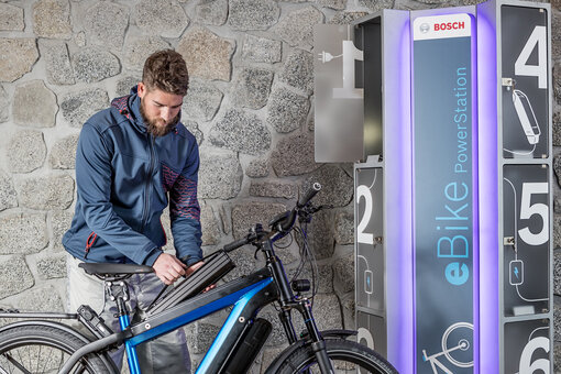 Fahrradfahrer baut PowerTube in Fahrradrahmen ein neben einer PowerStation