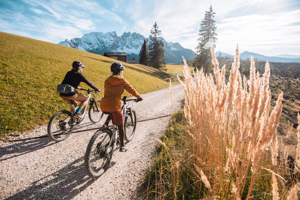 Due ciclista dell'eBike sono in tour in vacanza sostenibile. Sullo sfondo si vedono le Dolomiti in Alto Adige.