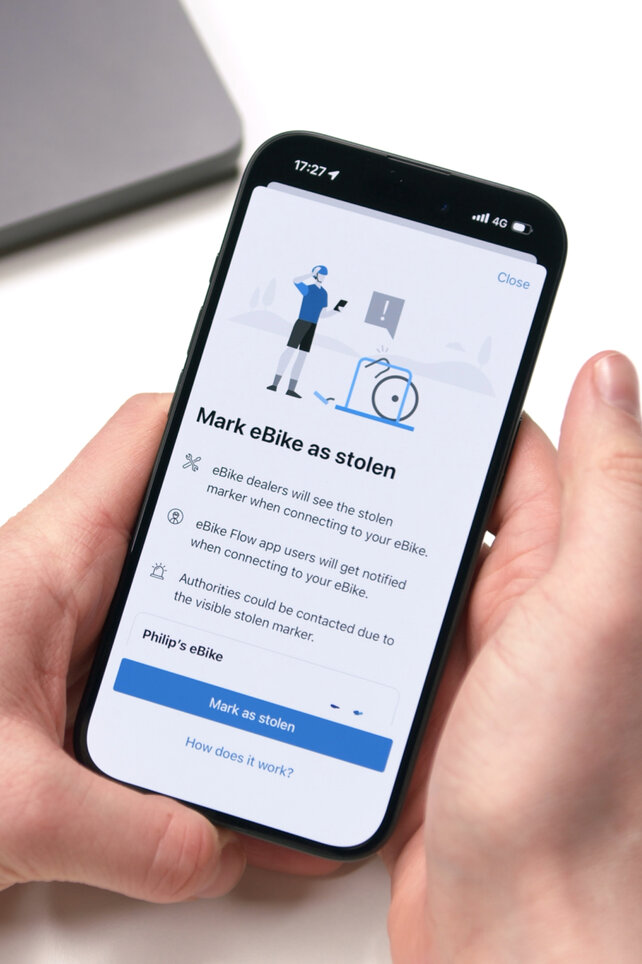 Close-up of a smartphone displaying the 'Mark eBike as stolen' function in the Bosch eBike Flow app. The display screen explains how marking your eBike as stolen informs specialist dealer/retailer and other app users about the theft when they attempt to connect.