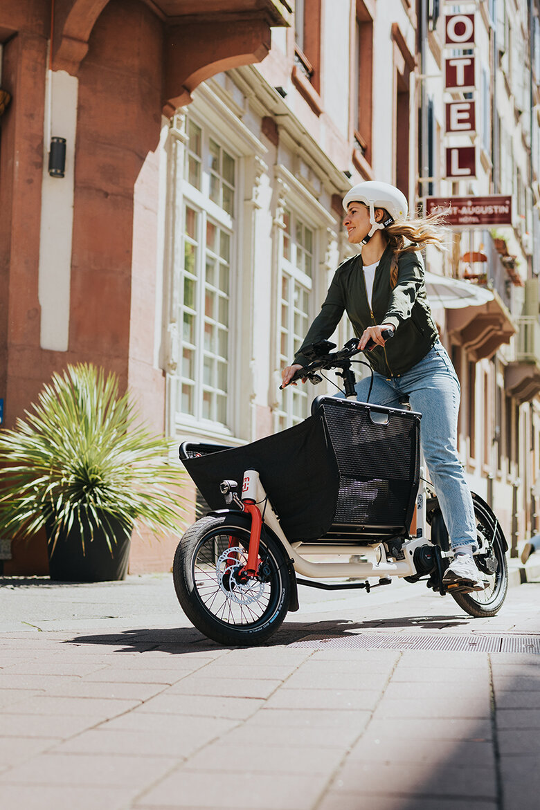 E-cyklista s cyklistickou helmou jede ve městě na nákladní elektrokolo Bosch.