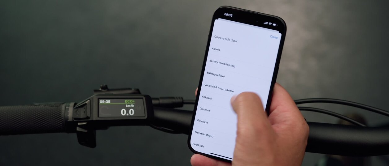 Bilde av en smarttelefon som gjør innstillinger for Purion 200, som er synlig i bakgrunnen.