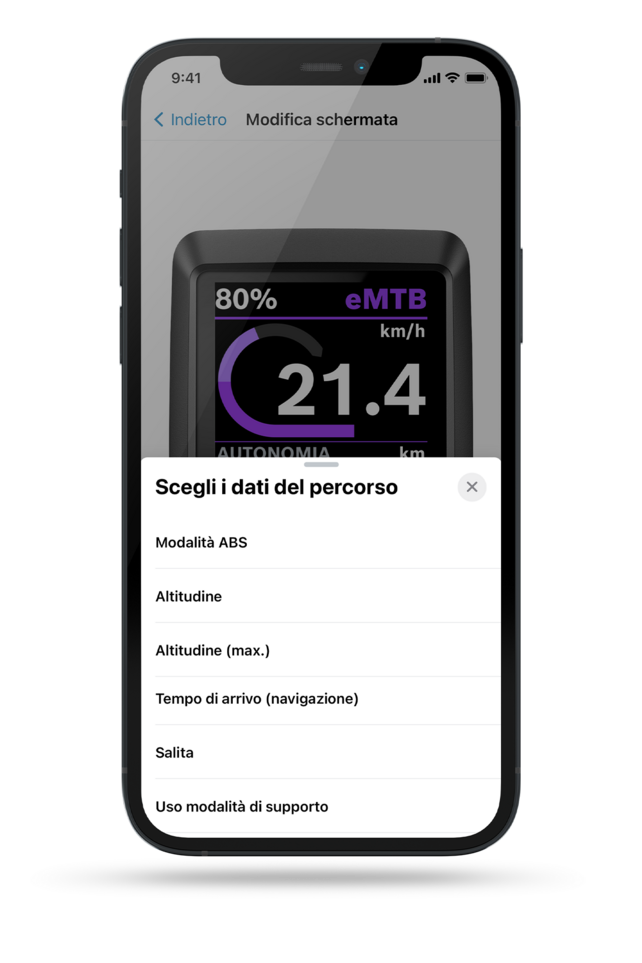 Schermata scattata da un display di telefono mostra un display Kiox sullo sfondo, in primo piano c'è un menu con il testo 'dati di marcia' da selezionare. Le opzioni includono: modalità ABS, batteria (eBike), batteria (telefono), ora di arrivo (navigazione), salita, tempo di frenata.