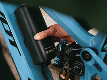 En person monterar ett Bosch PowerMore 250 batteri på en blå elcykel.