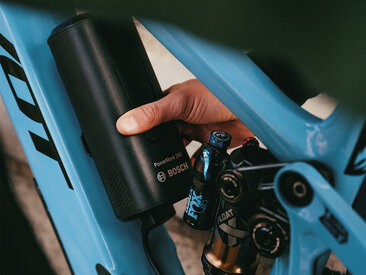 En person monterer en Bosch PowerMore 250 batteri på en blå eMountainbike.