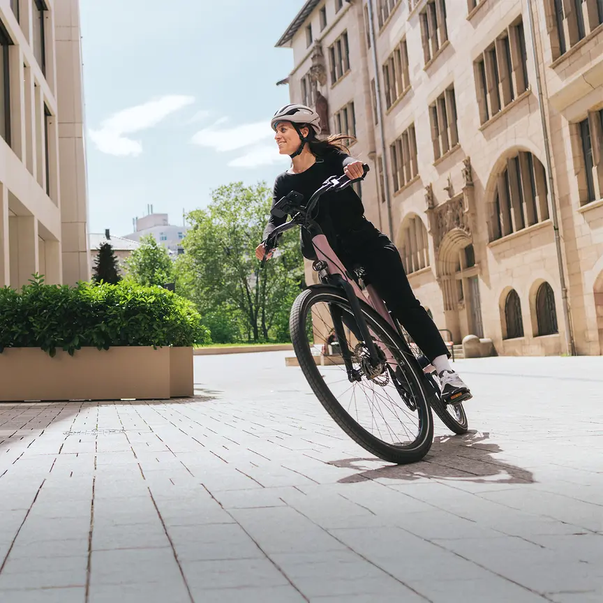 A woman rides a modern city eBike dynamically through a sunny urban environment.