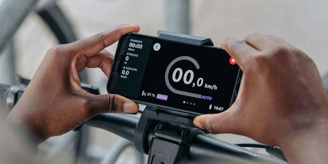A person aligns a phone with the flow app open on the phone grip of a handlebar.