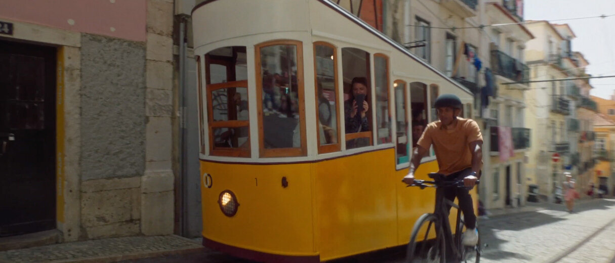 Ein eBike Fahrer fährt neben einer Straßengondel eine Pflastersteinstraße hinauf, im Hintergrund erkennt man Häuser.