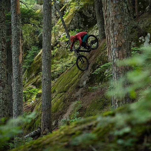 eBike-cyklisten cyklar nerför en brant sluttning i skogen.
