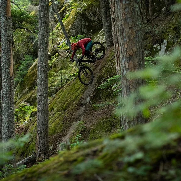 eBike Fahrer fährt im Wald einen steilen Abhang hinunter.