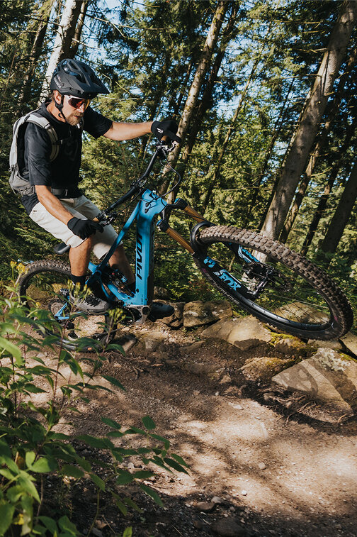 An eBiker performing a wheelie around a curve in a forest.
