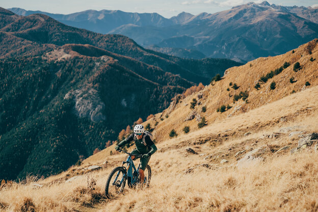 Mann fährt mit einem eBike einen steilen Hang hinauf, umgeben von einer beeindruckenden Berglandschaft.