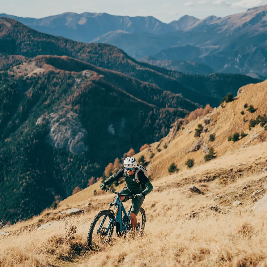 Mann fährt mit einem eBike einen steilen Hang hinauf, umgeben von einer beeindruckenden Berglandschaft.