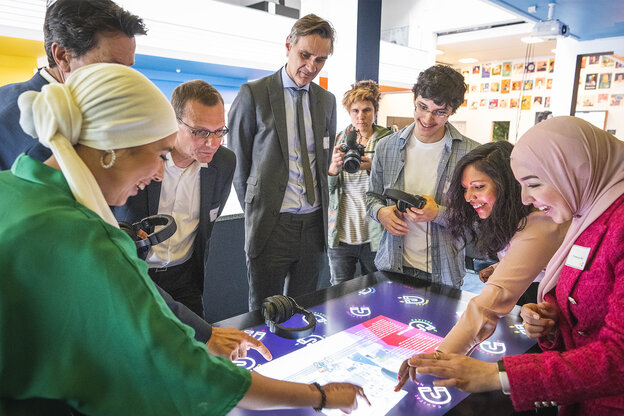 Een groep mensen staat rondom een groot display en gebruikt het interactief.